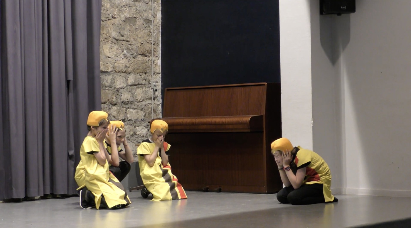 Enfants en costumes jaunes jouant une scène sur scène